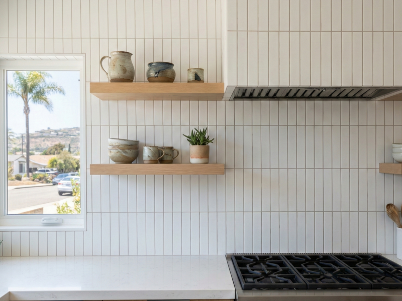 Modern Encinitas kitchen backsplash installation with vertical white matte tiles, floating white oak shelves, and a professional range.