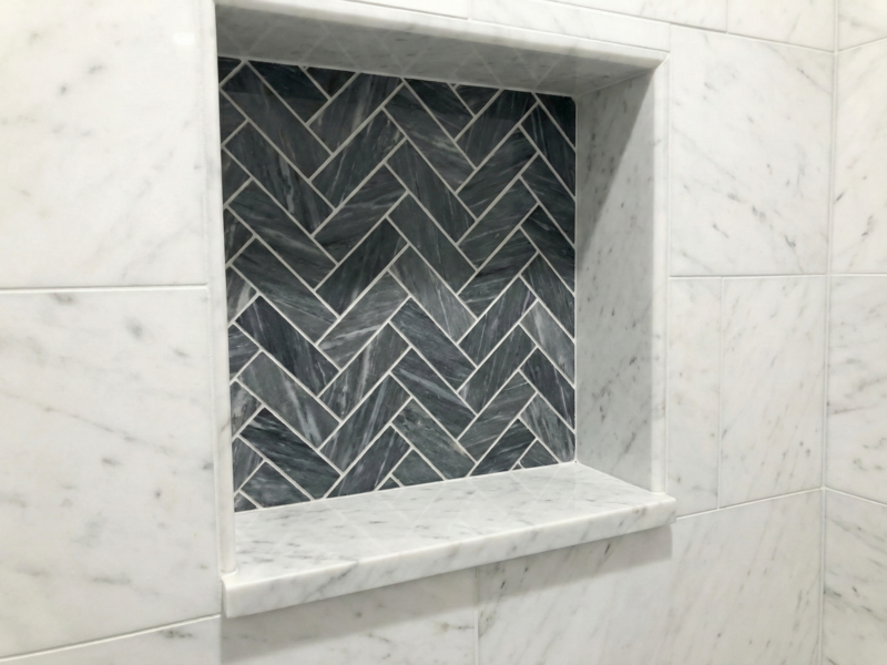 Tiled Shower Niche Detail. A close-up "just tile" view of a completed shower niche, featuring a contrasting herringbone pattern and a marble shelf.